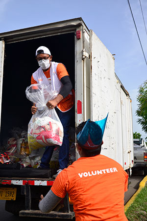 Voluntarios apoyan a movilizar kits de alimentos.