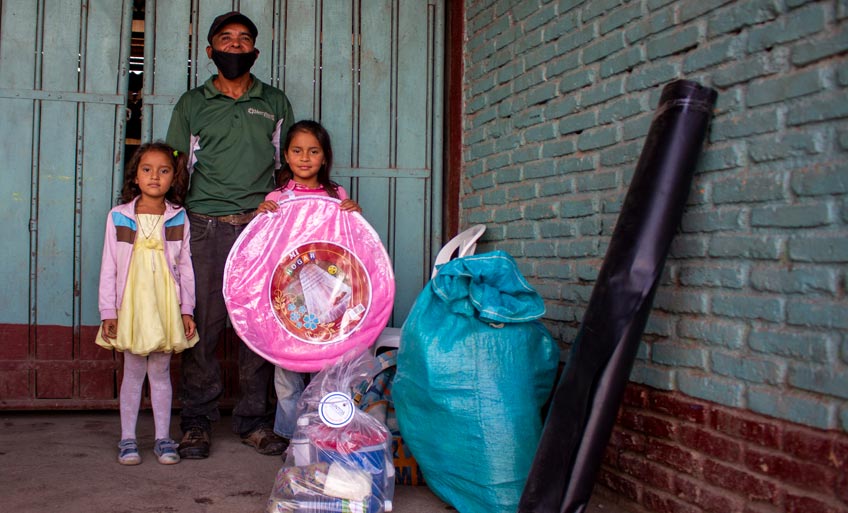 Jenny (6) y Nancy (8), contentas junto a su papá, Pablo, reciben paquete alimenticio y otros insumos. Su vivienda fue dañada por los vientos y las lluvias.