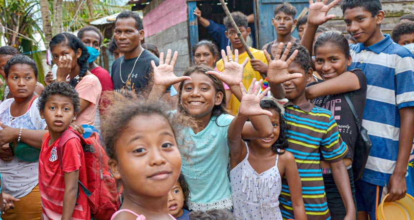 Niñas y niños hacen fila para recibir alimentos en comedor comunitario.