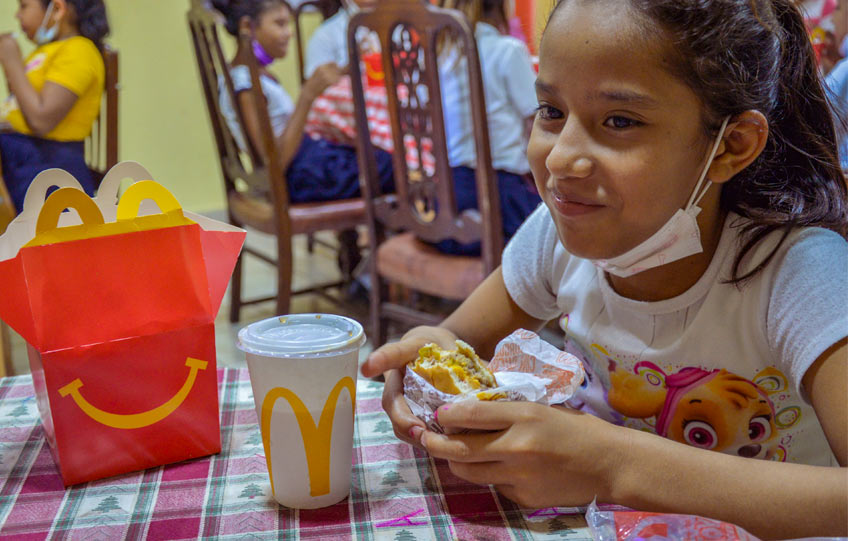 Niña disfruta de Cajita Feliz donada por McDonald's Nicaragua.