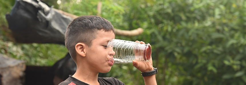 Niño tomando agua limpia y segura